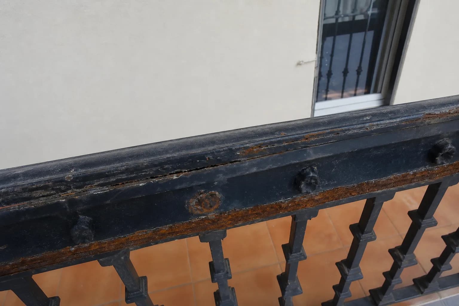 Detalle de corrosión y pérdida de pintura en una barandilla metálica